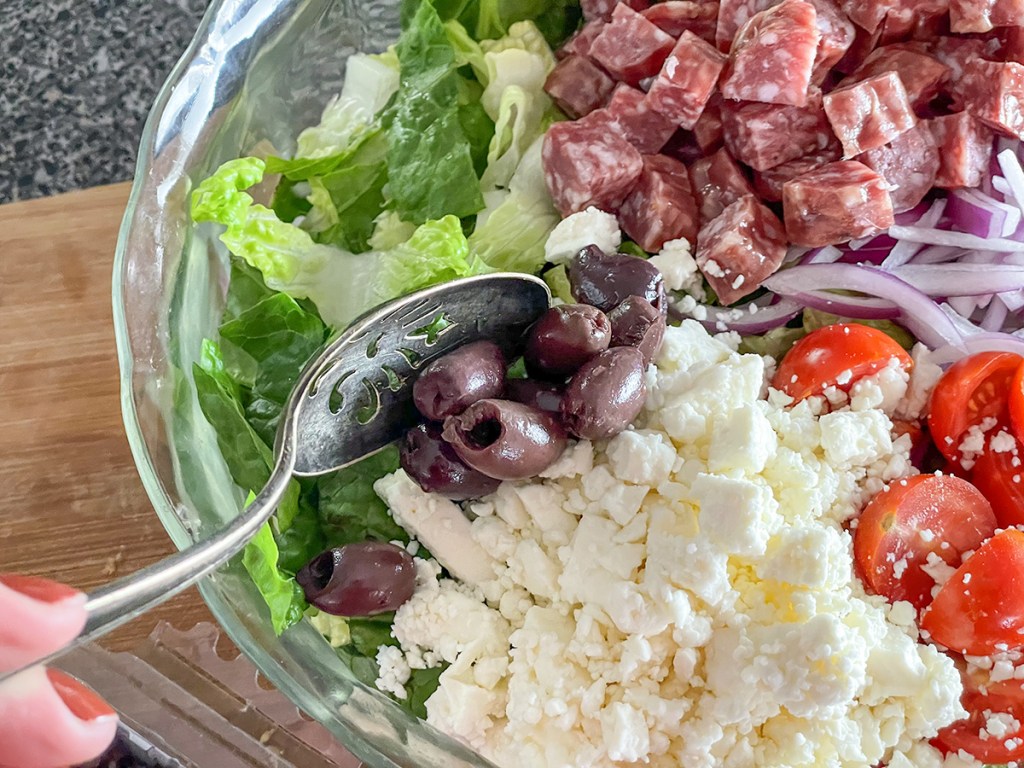 putting kalamata olives on a salad 