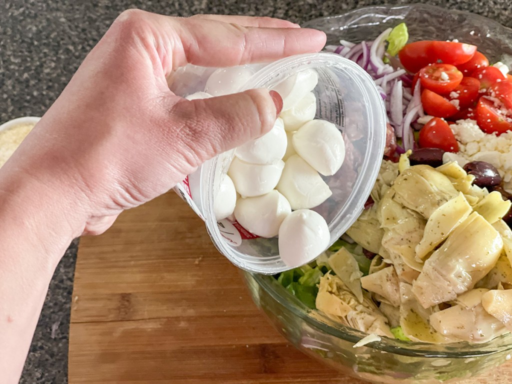 adding fresh mozzarella to salad 
