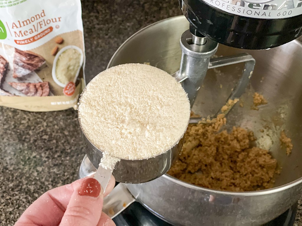 adding almond flour to a mixing bowl