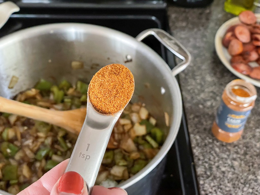 adding cajun seasoning to a stockpot 