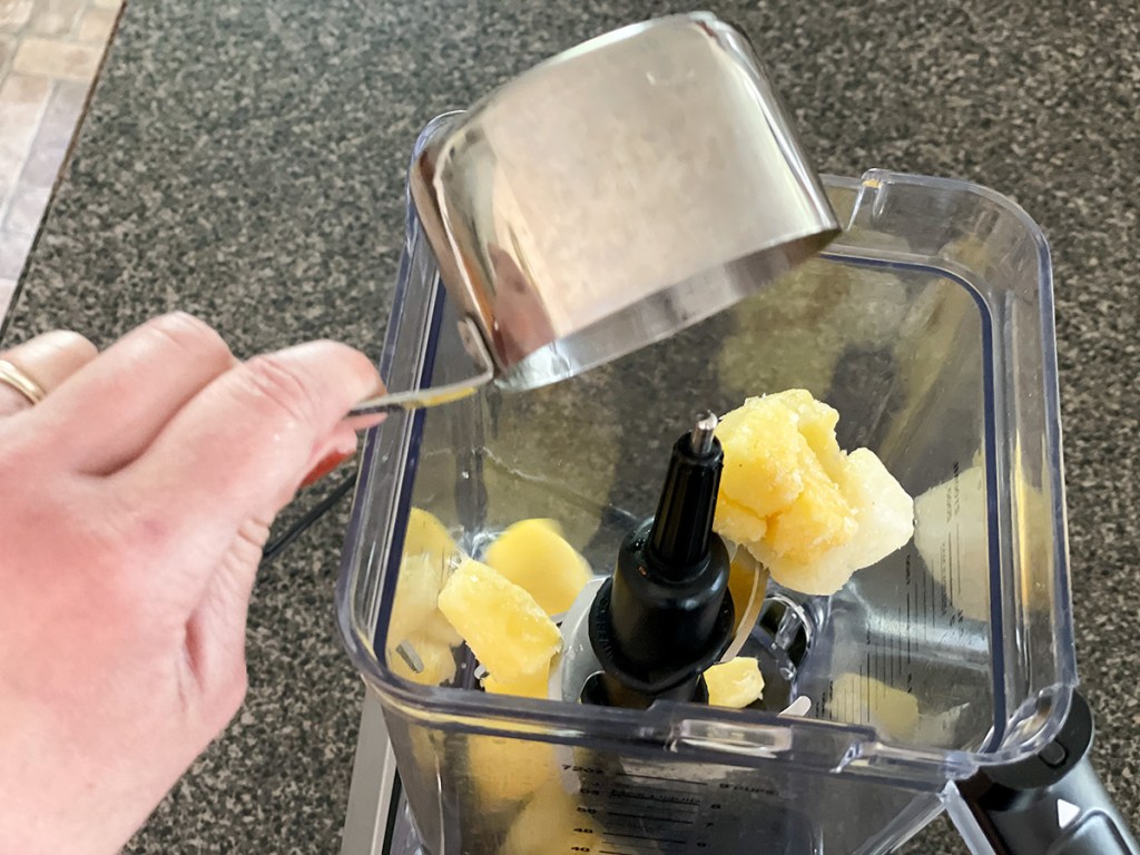 putting frozen pineapple chunks in a blender