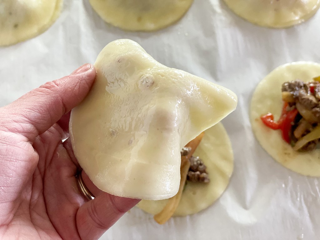 putting a slice of provolone over Philly cheesesteak filling 