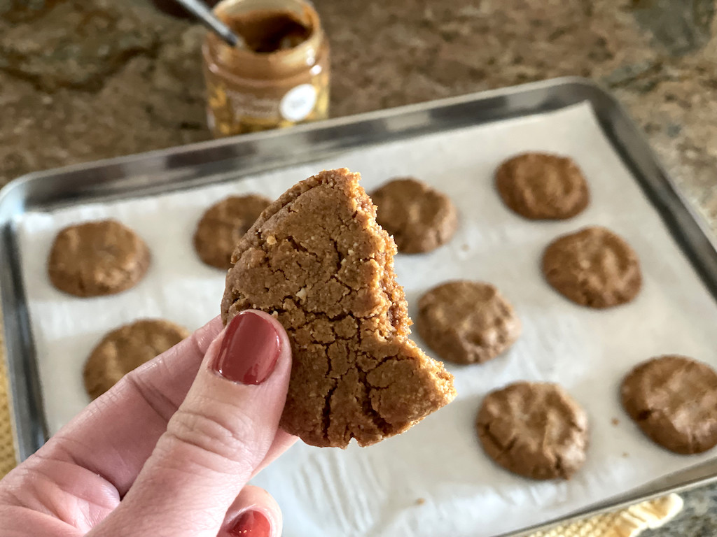holding Choczero keto cookie butter cookie with cookies on pan