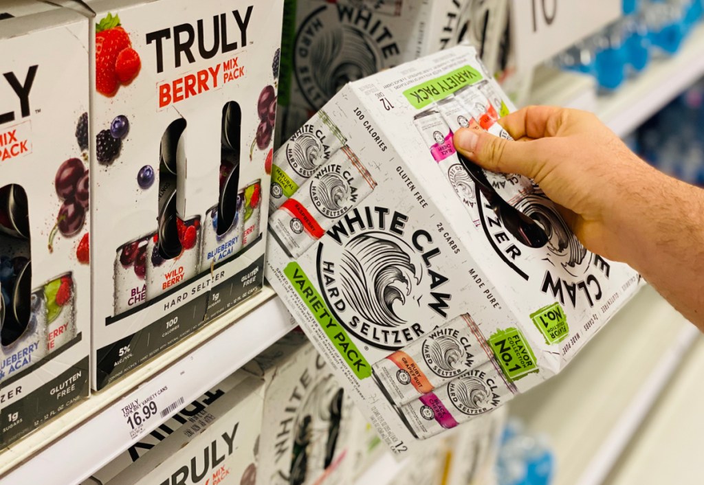 hand grabbing a package of white claw low carb seltzer off the shelf