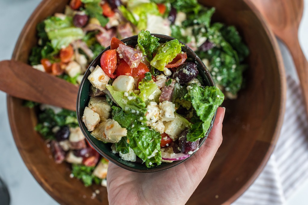 holding a bowl of keto antipasto salad