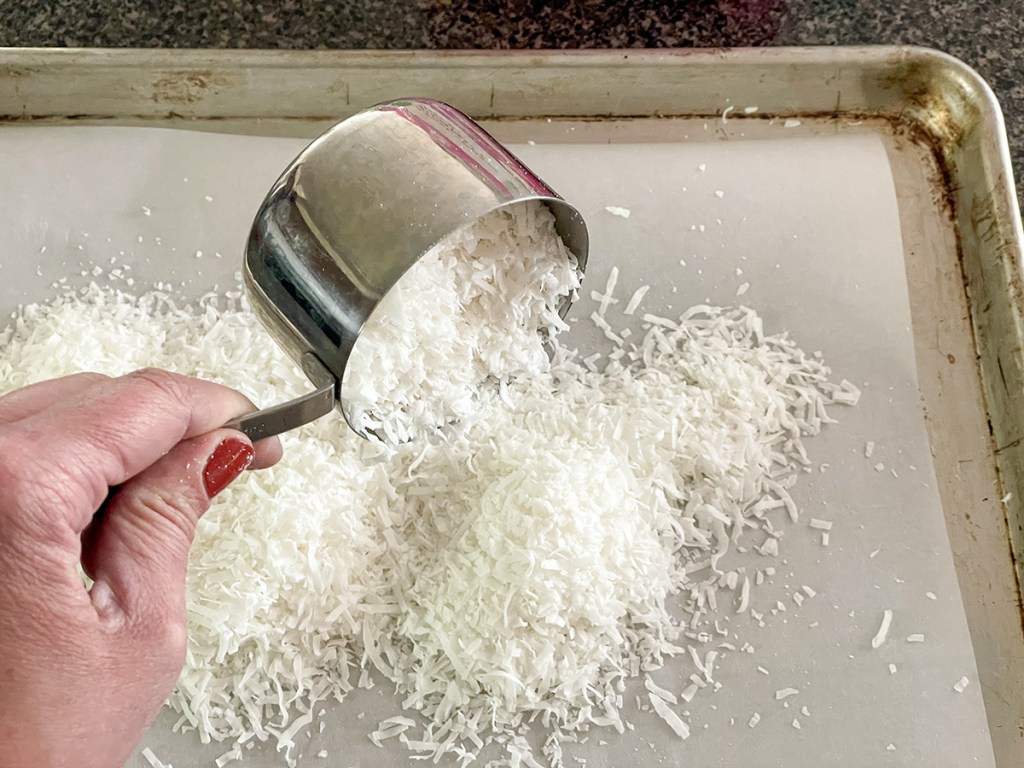 pouring coconut on a baking sheet 