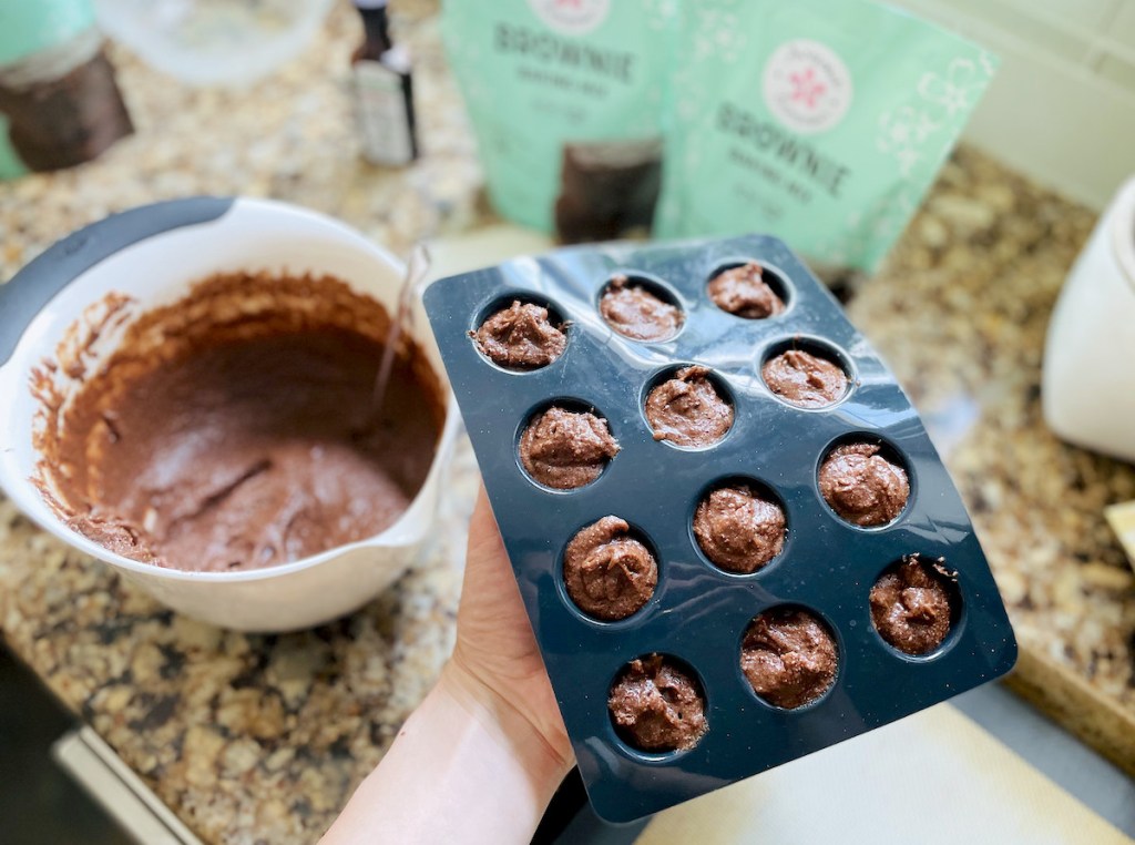 hand holding a silicone mini muffin tin with keto brownie mix inside