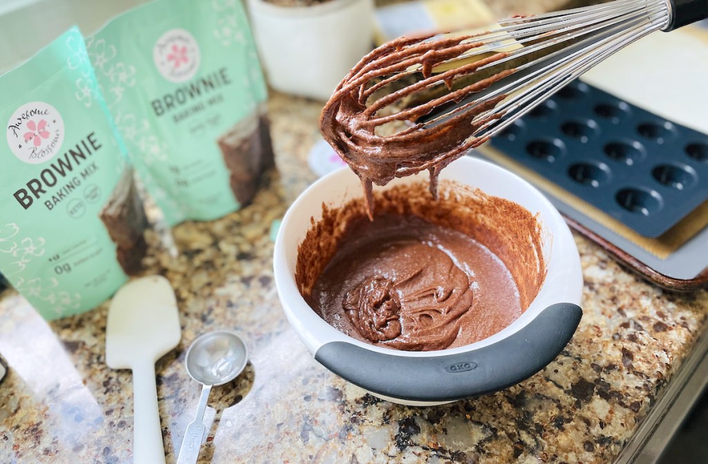 whisk with brownie mix in bowl with keto brownie mix on counter