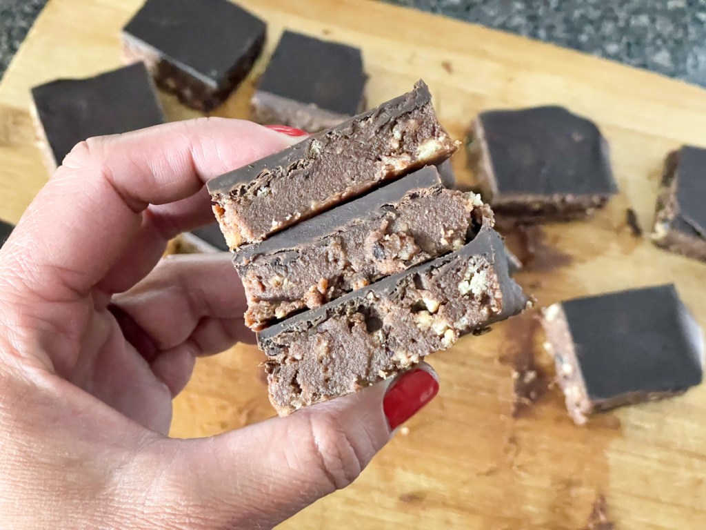 holding a stack of keto chocolate no bake cookie bars 
