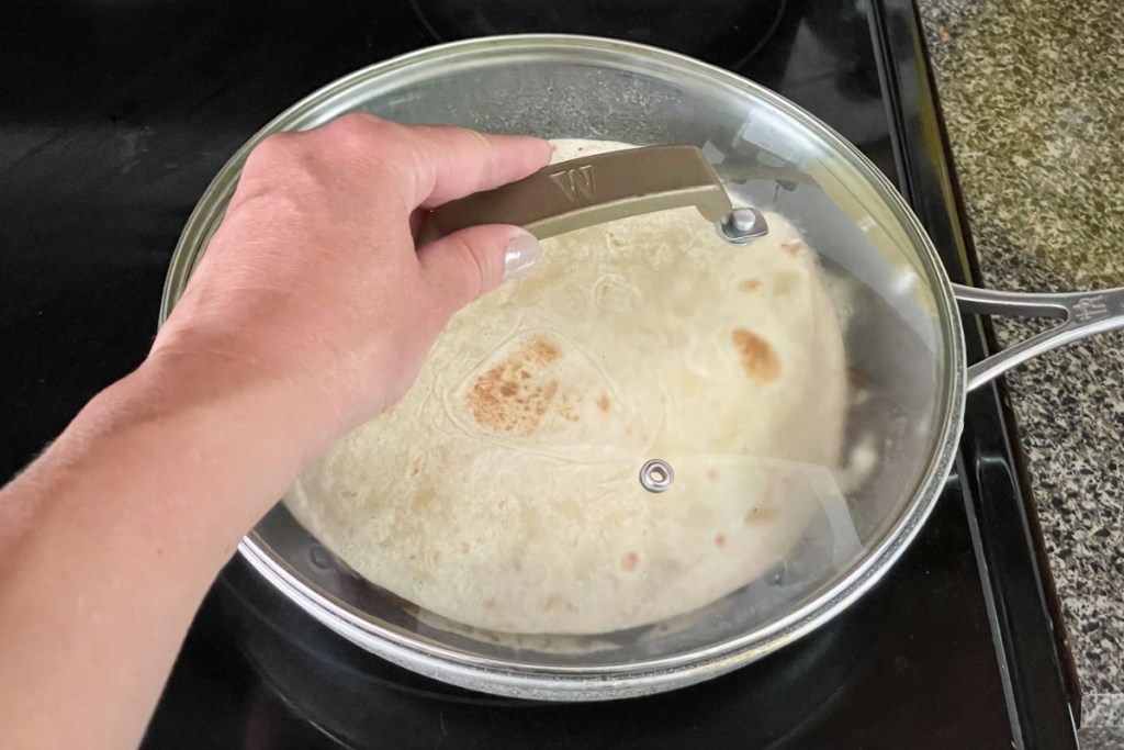 covering steak quesadilla in skillet with a lid