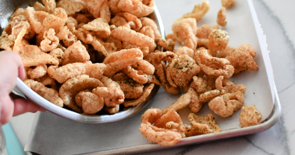 adding pork rinds to a sheet pan