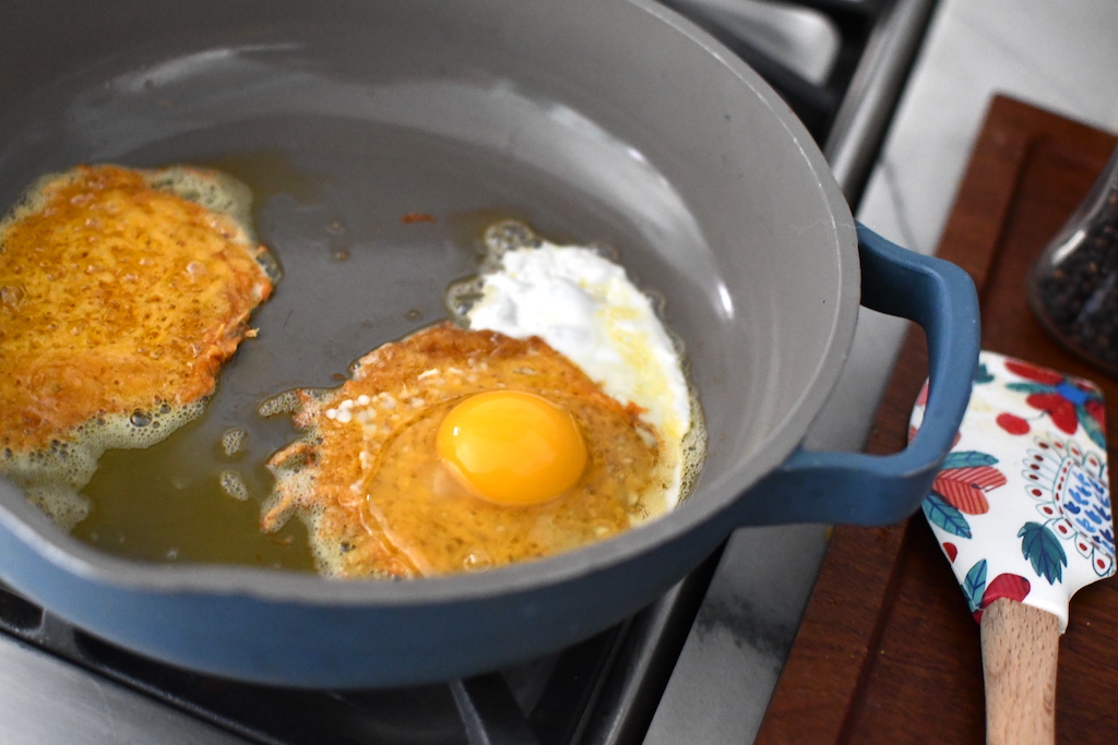 cooking fried eggs and cheese in pan 