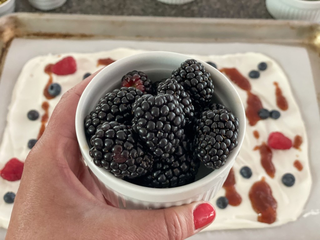 holding a bowl of blackberries