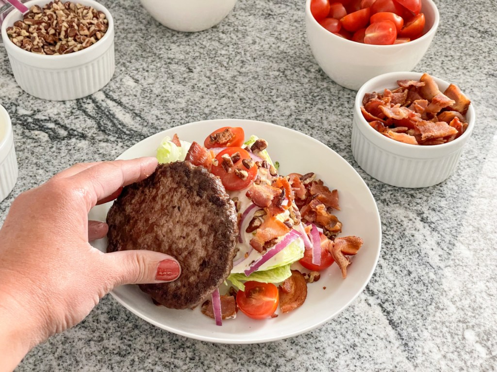 adding a hamburger patty to a wedge salad