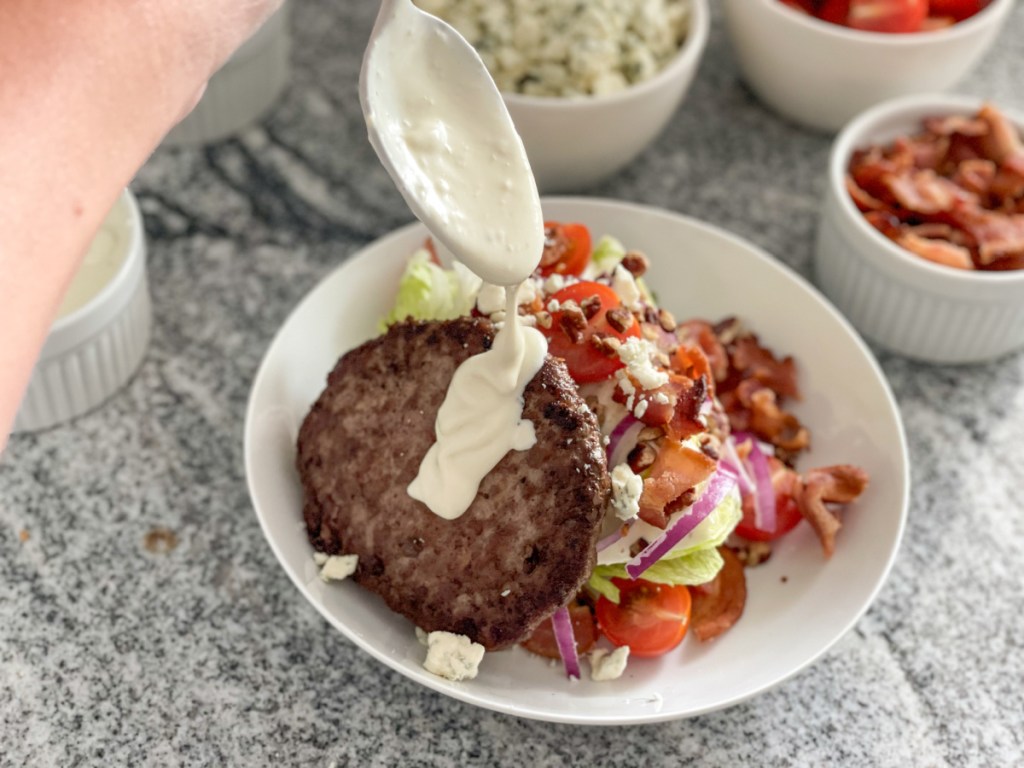 putting blue cheese dressing on a wedge salad