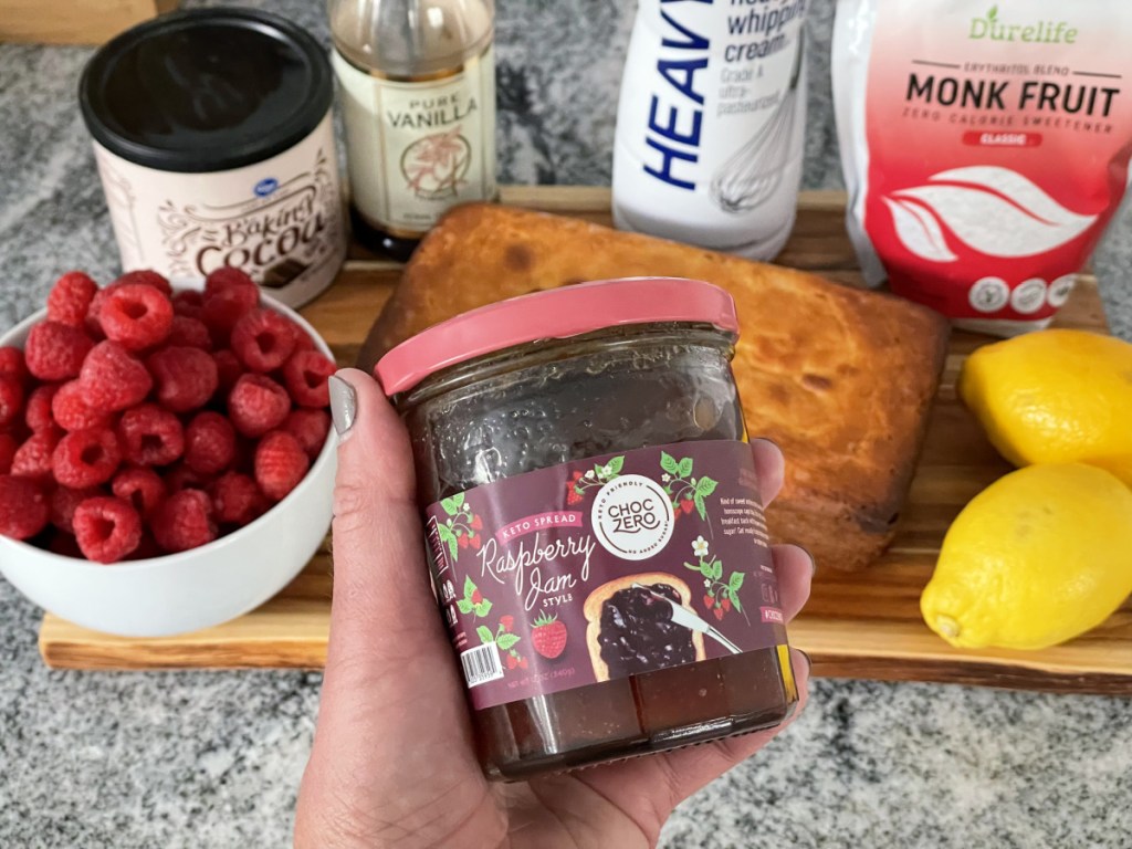 holding jar of ChocZero Keto Raspberry Jam