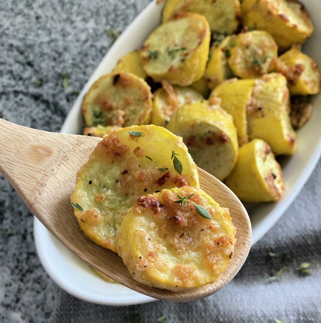 spoon scooping roasted summer squash that was baked in the oven and sprinkled with garlic