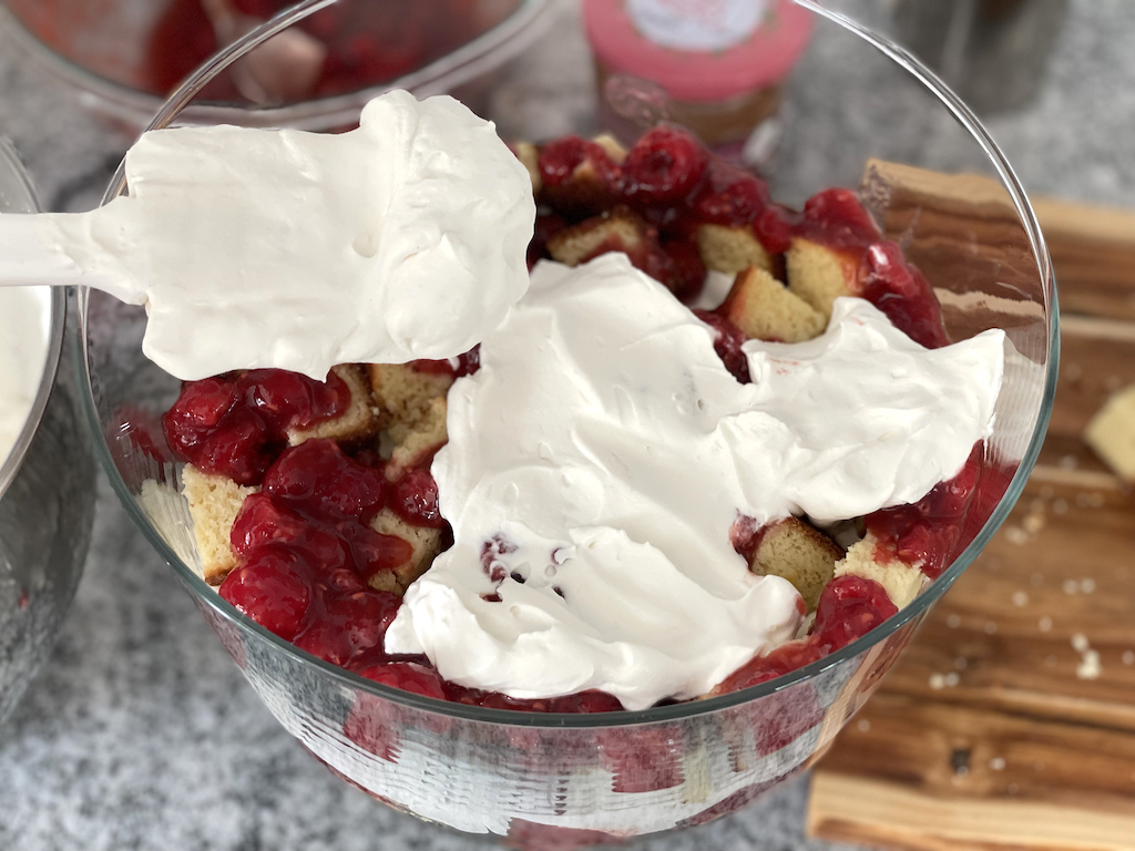 putting whipped cream on keto berry trifle 