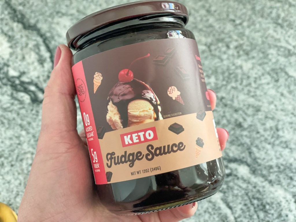 holding jar of choczero keto hot fudge sauce