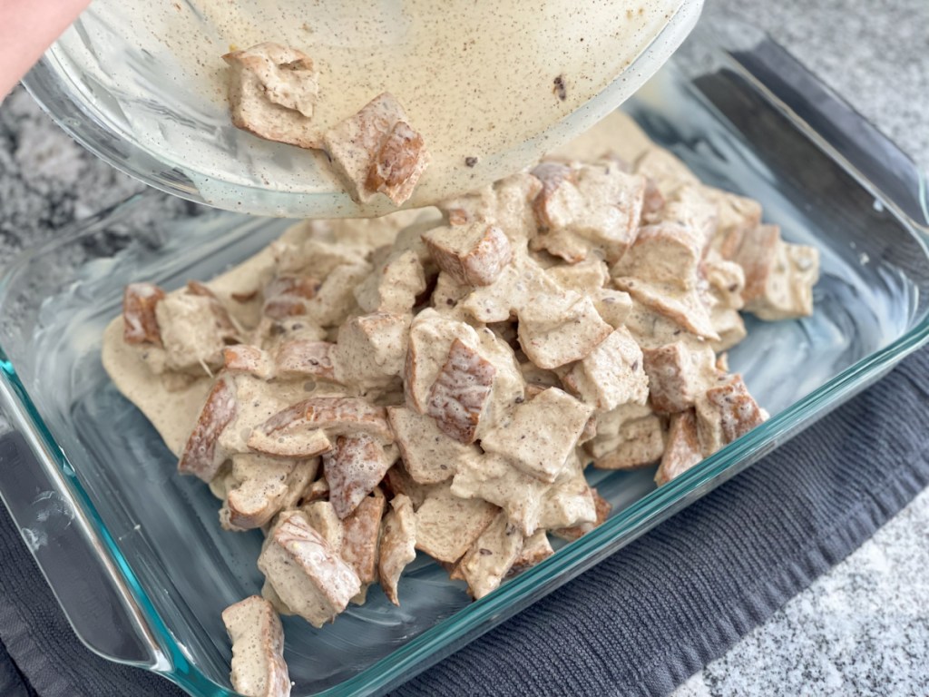 pouring soaked bread cubes into baking dish