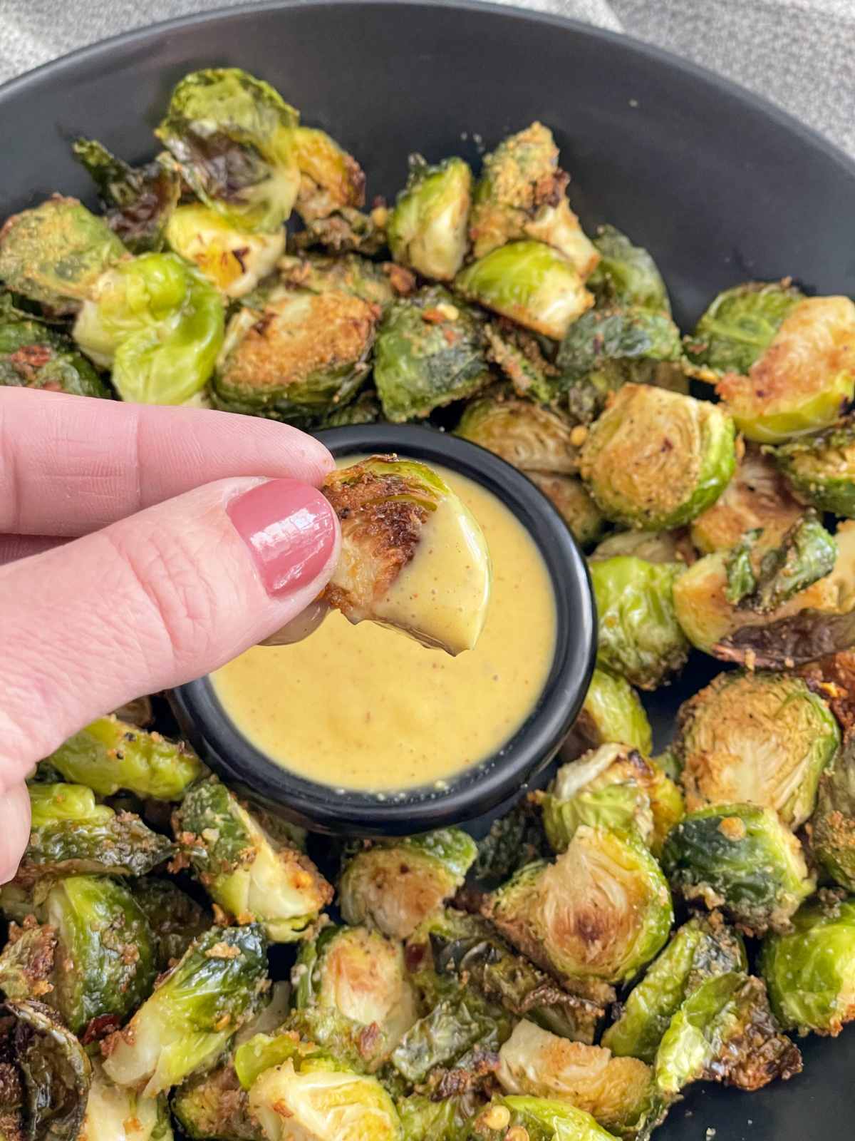 dipping Brussels sprout into keto honey mustard sauce