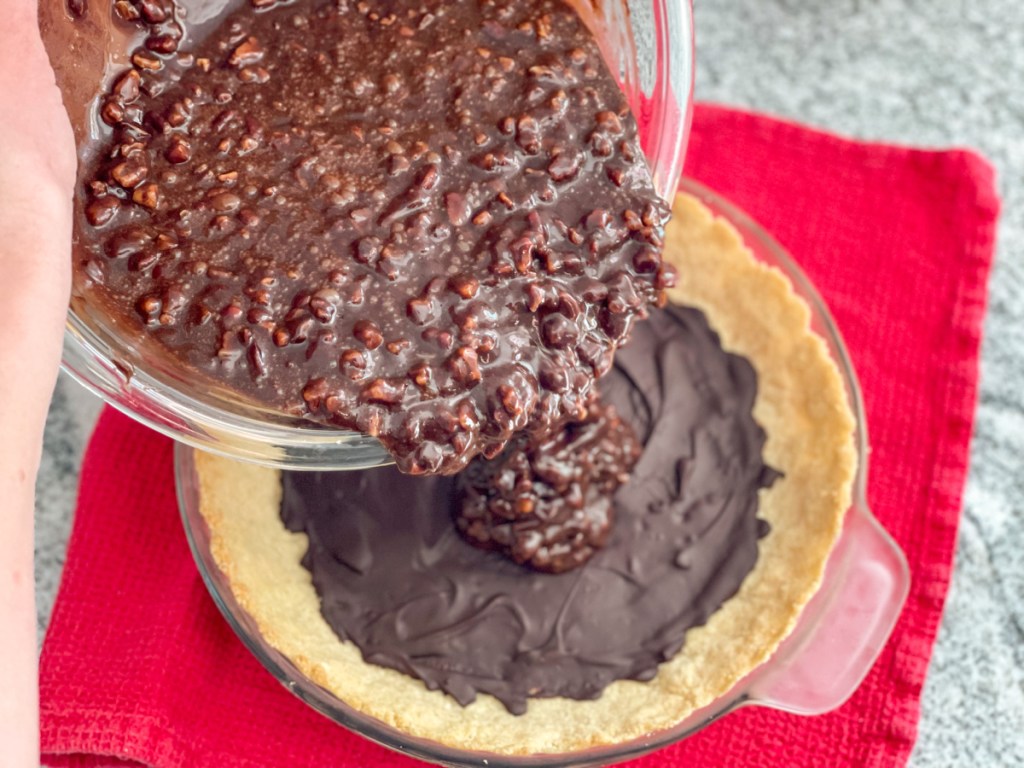 pouring chocolate fudge pie filling into pie crust