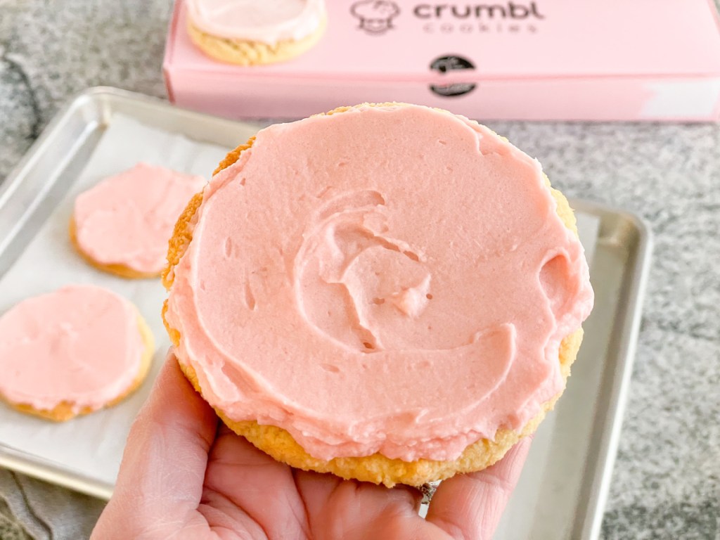 holding a keto crumbl pink sugar cookie
