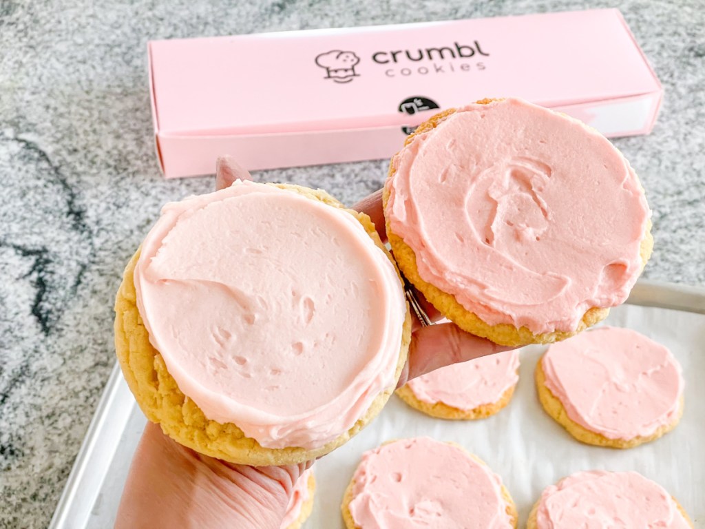 holding a keto crumbl pink sugar cookie and a Crumbl Pink Cookie