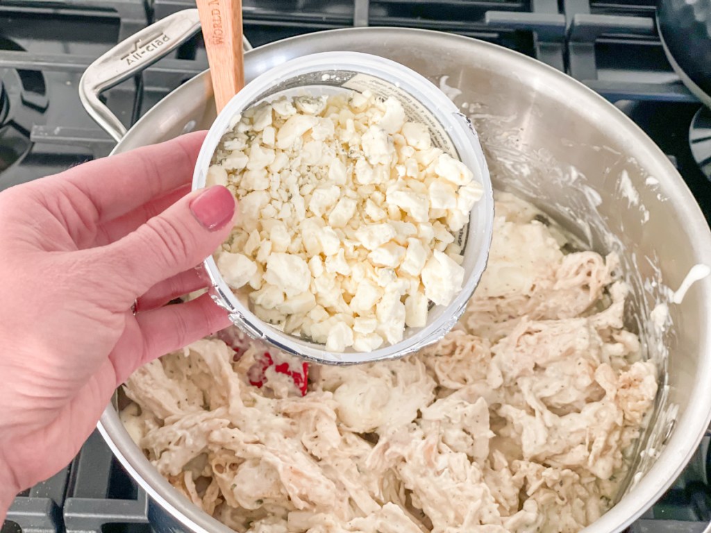 holding container of blue cheese crumbles to add to chicken mixture