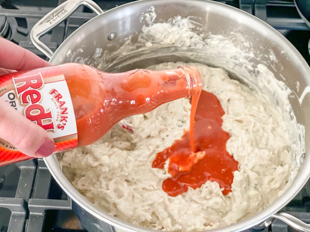 adding Frank's Hot Sauce to shredded chicken mixture