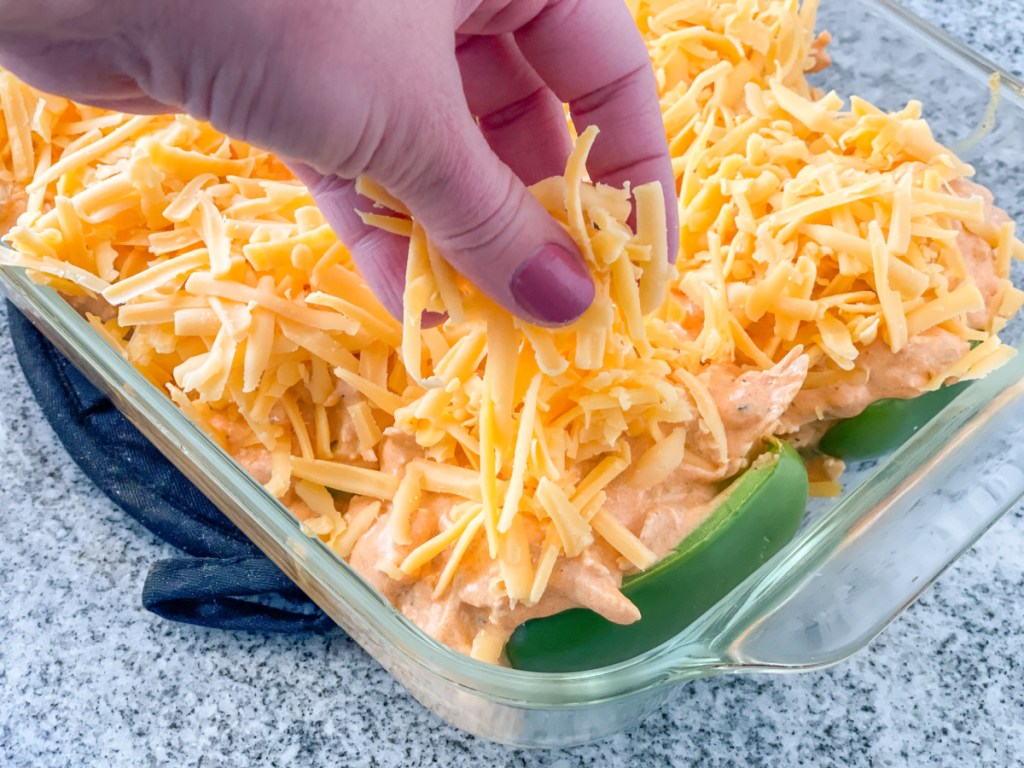 adding shredded cheddar to buffalo chicken stuffed peppers 