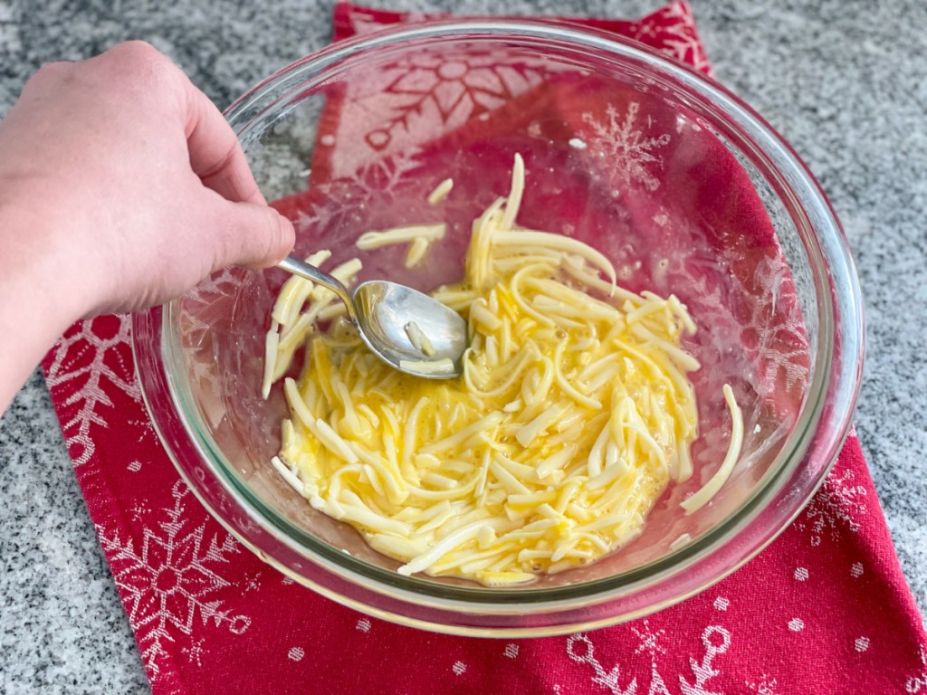 mixing together egg and shredded cheese