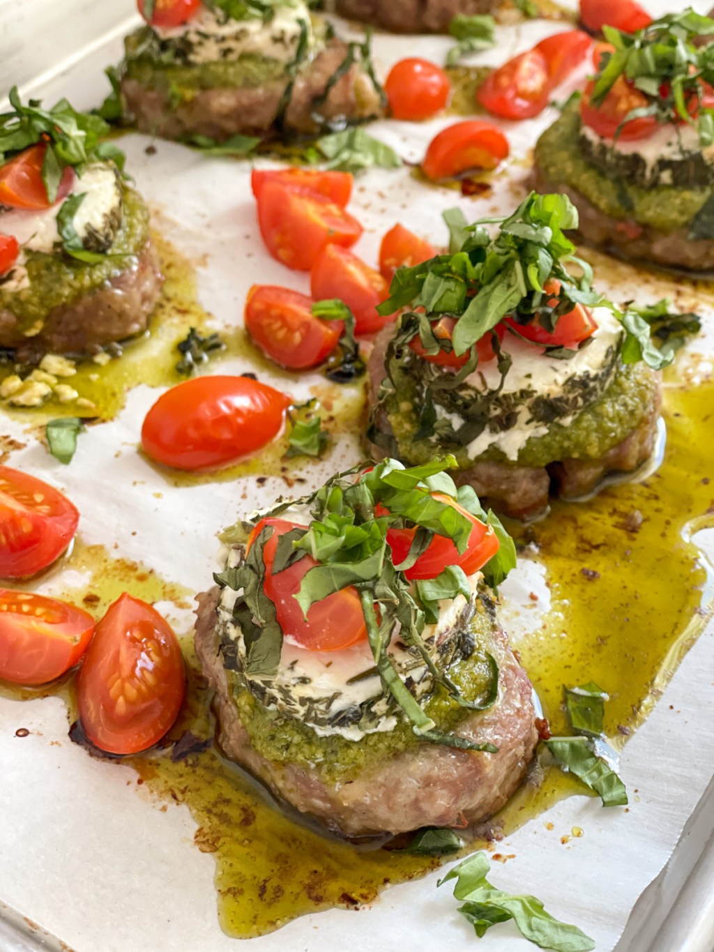 sausage bites with pesto, goat cheese, tomatoes on baking sheet 