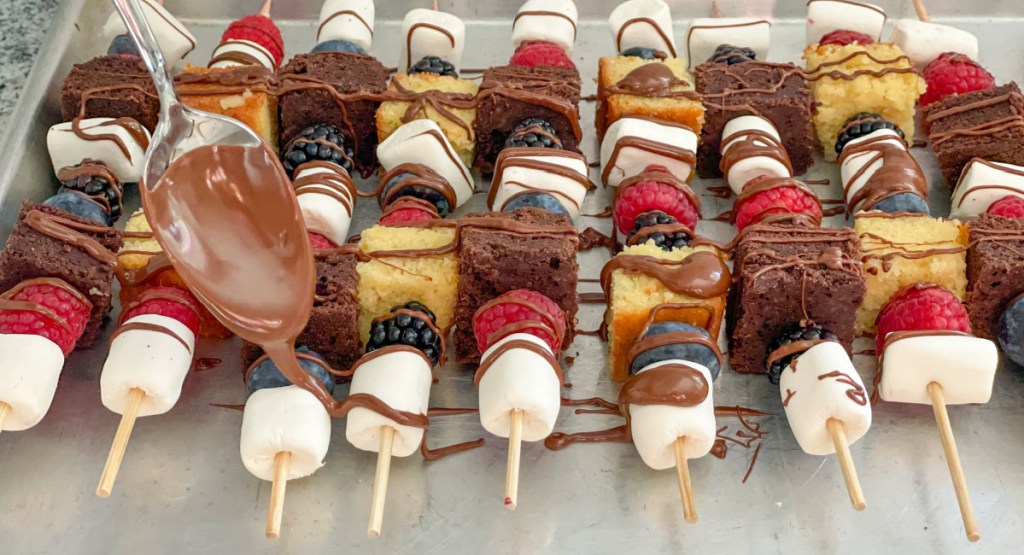 drizzling chocolate over dessert kabobs