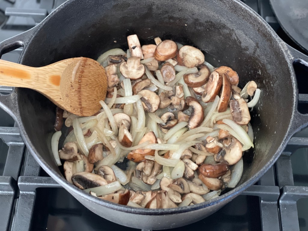 onions and mushrooms sautéing in a Dutch oven