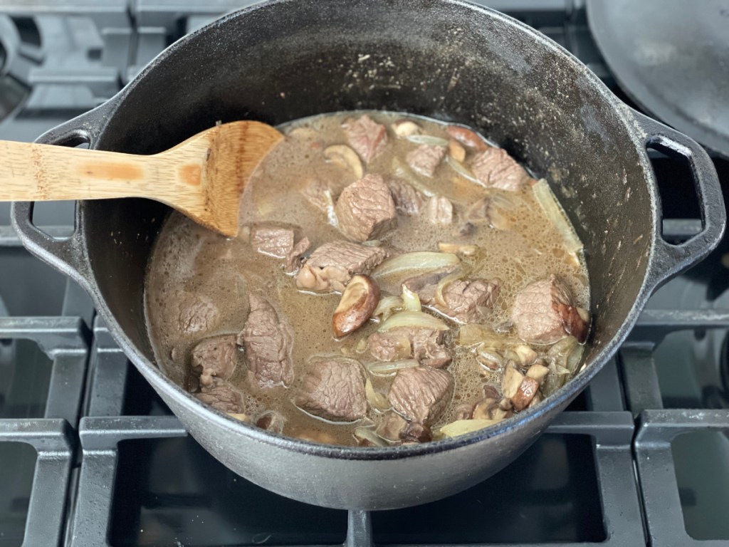 simmering beef tips in broth with onions and mushrooms 