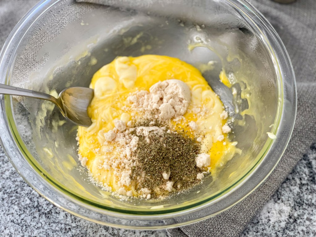 mixing together melted mozzarella, egg yolks, almond flour, and seasonings in a bowl