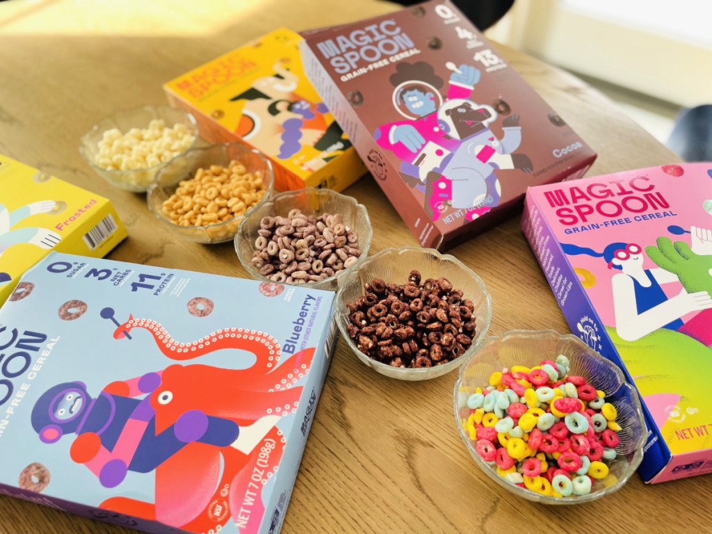 Several bowls and boxes of Magic Spoon Cereal Flavors sprawled out on a kitchen table