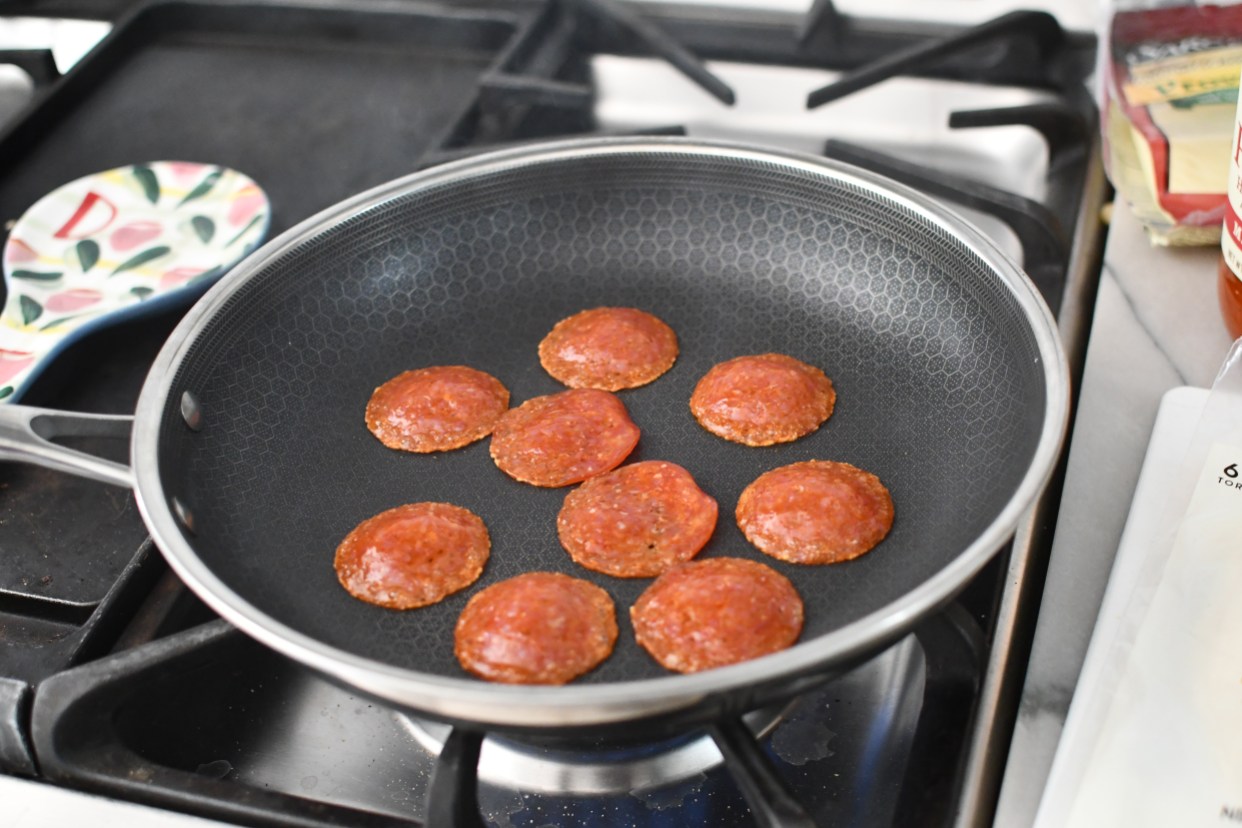 adding pepperoni to a skillet