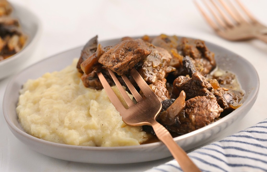 forkful of keto beef tips on mashed cauliflower