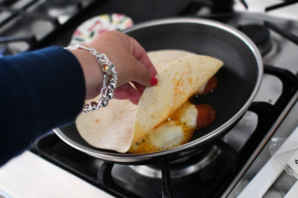 placing a tortilla on top of cheese on a skillet