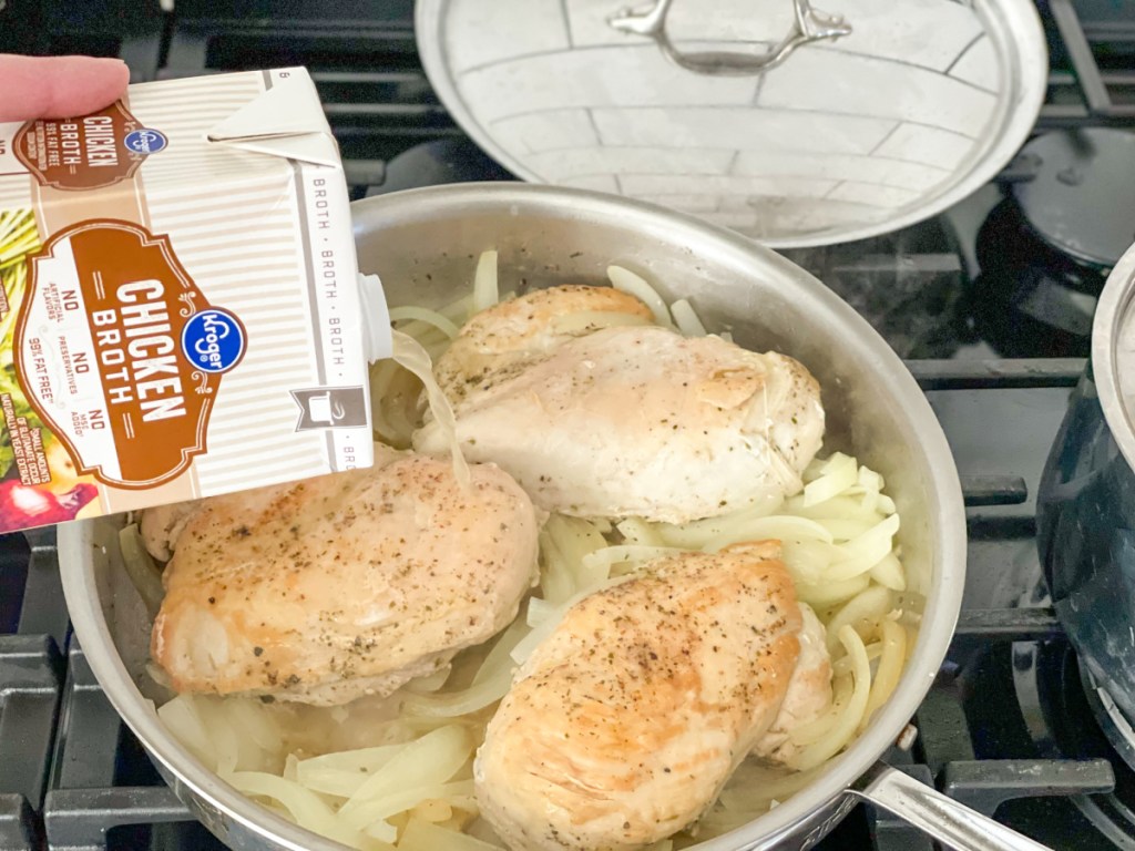 adding broth to a skillet with chicken