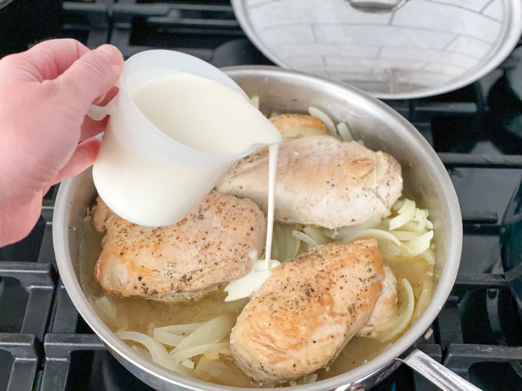 adding heavy whipping cream to a skillet with chicken