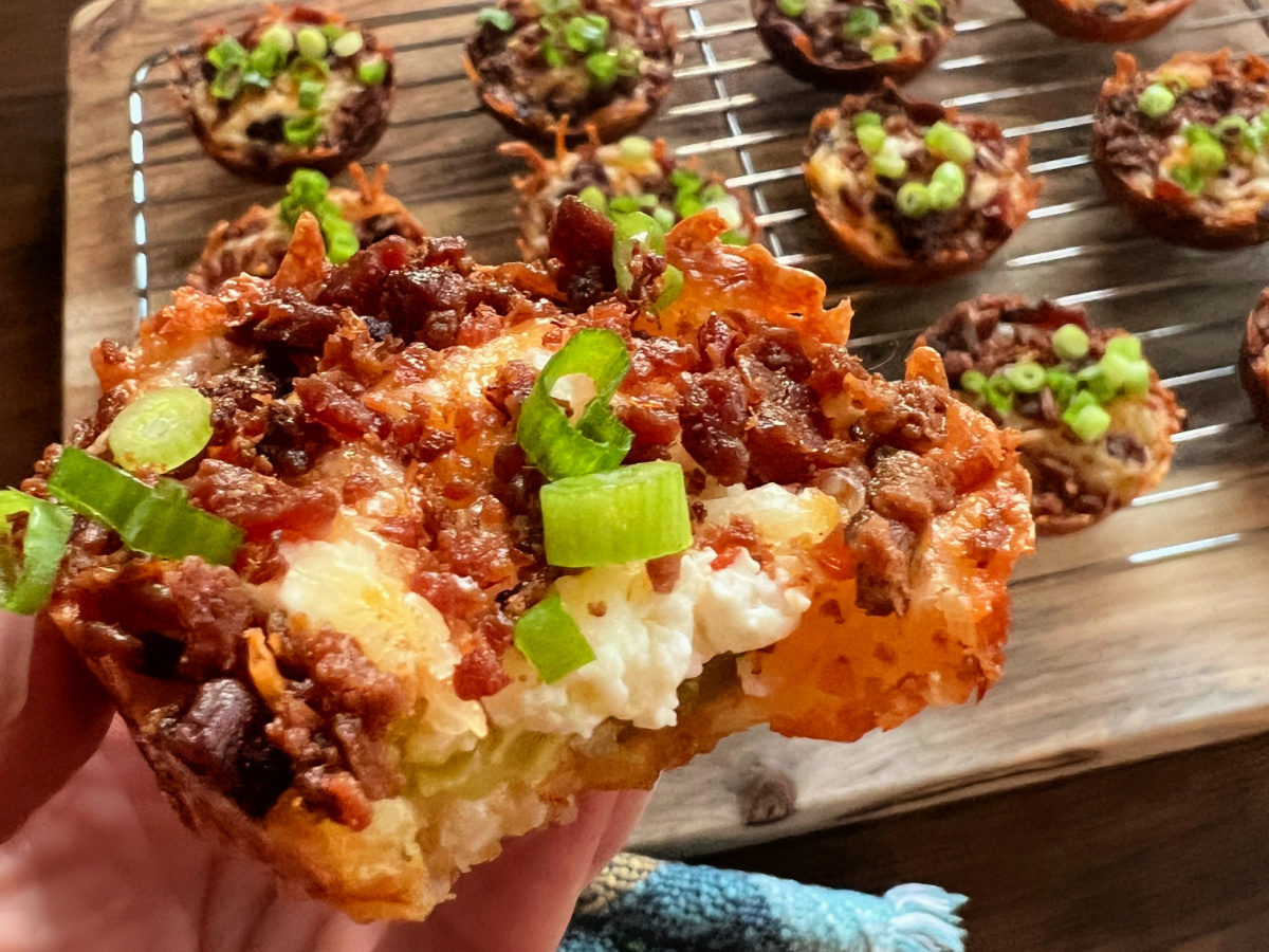 A hand holding a jalapeño popper appetizer with a bite taken out of it.