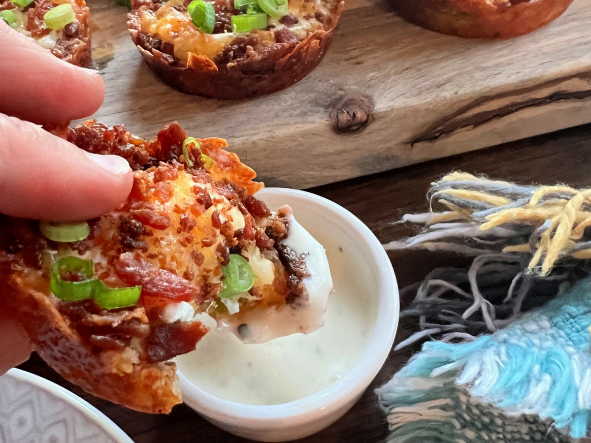 Hand dipping jalapeño popper bite into ranch dressing.