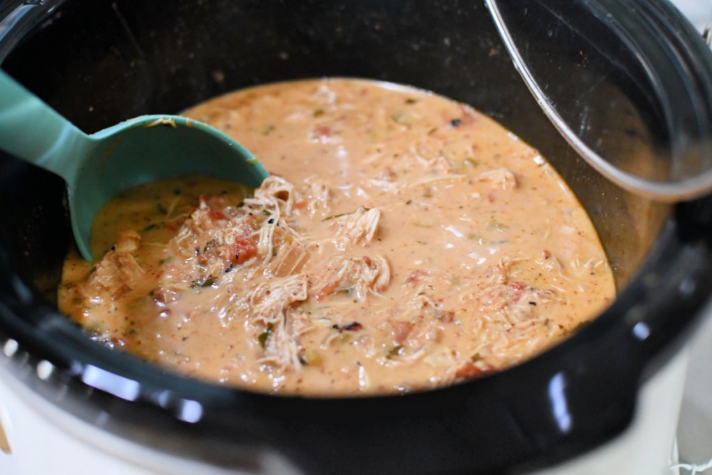 Stirring a slow cooker batch of copycat chick-fil-a keto chicken tortilla soup after cooking.
