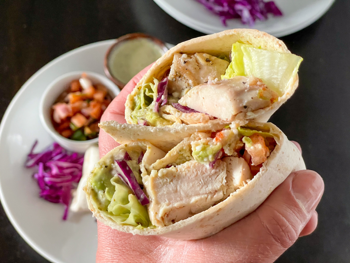 holding a keto burrito cut in half