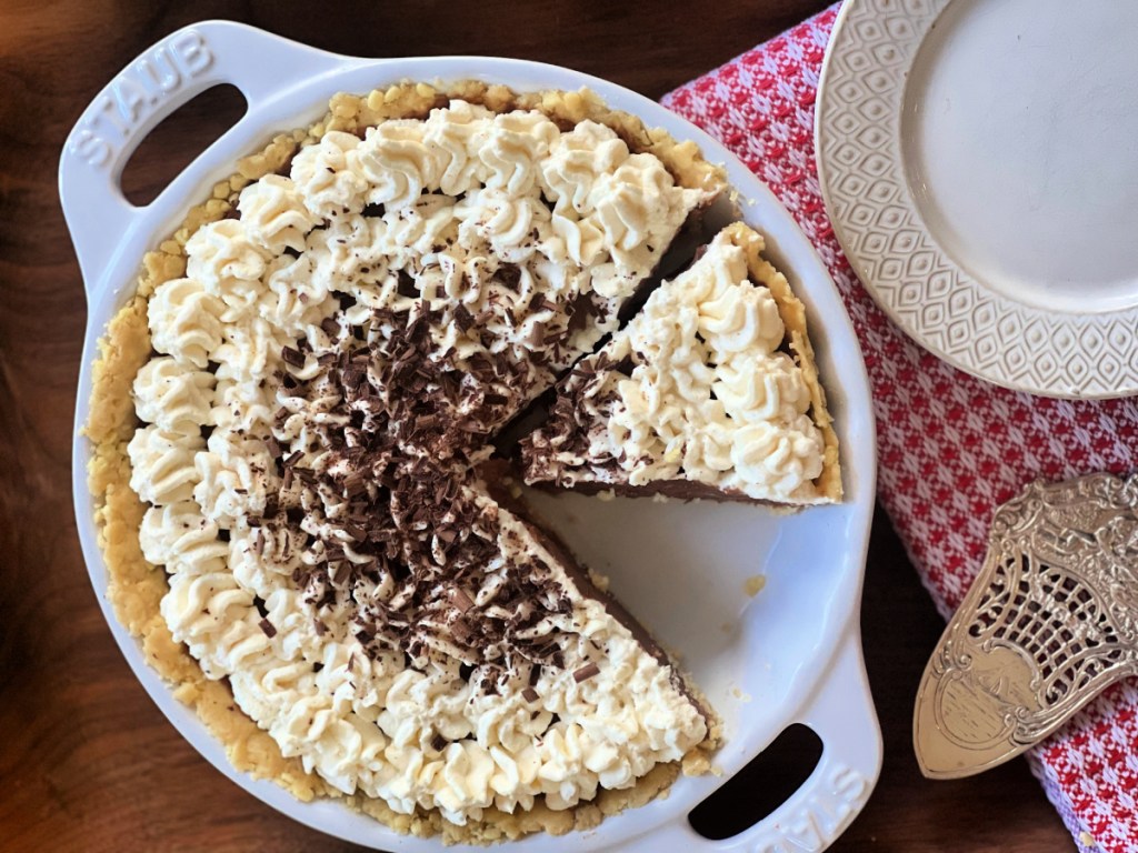 Keto chocolate cream pie in a pie plate with a slice cut and ready to serve