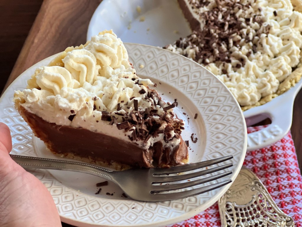 Hand holding a plate with a slice of keto chocolate pie.