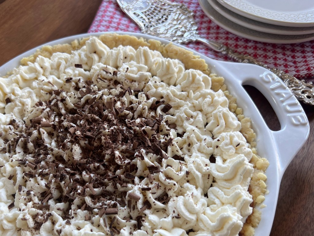 Chocolate cream pie on a table next to serving plates